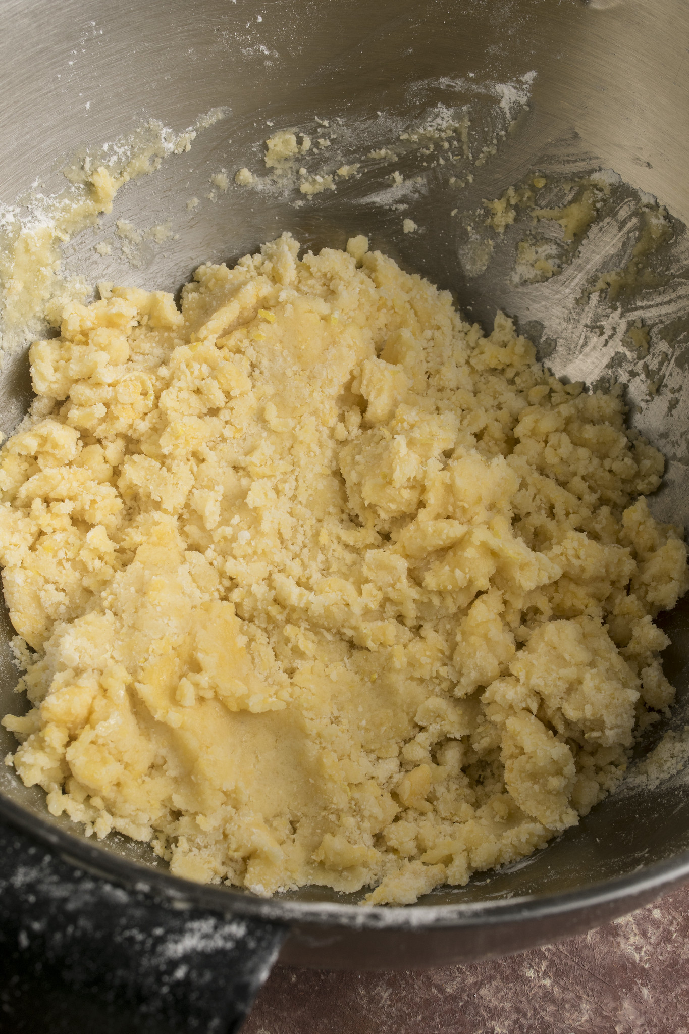 Close-up of the soft crumbly dough for sbriciolata ai frutti di bosco in a mixing bowl, showing the rustic texture before pressing into the tin.